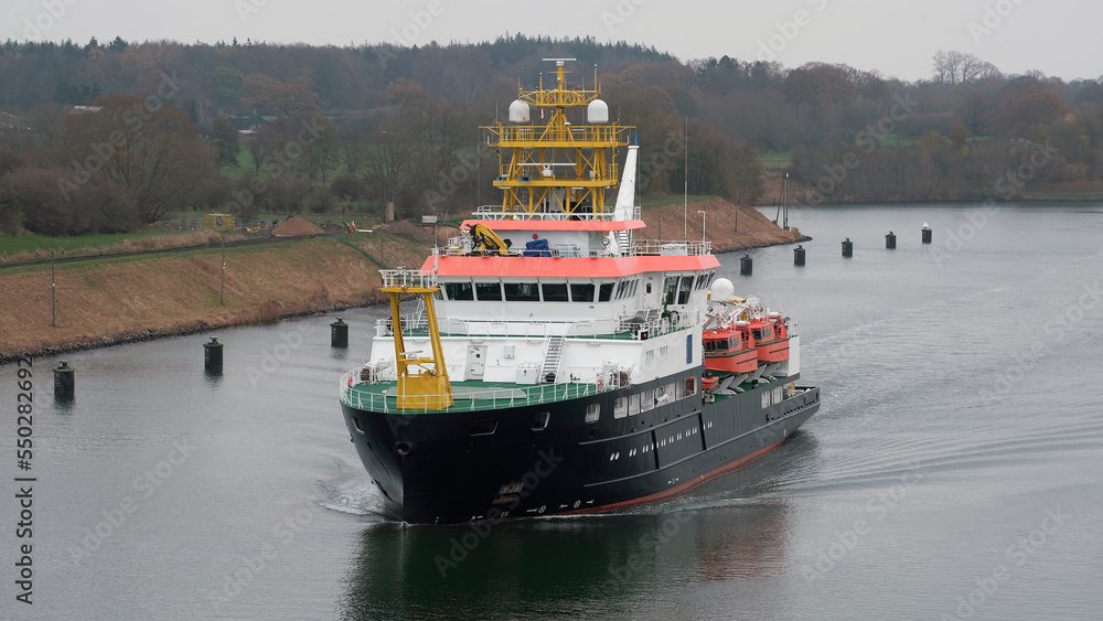 Kiel Canal, Germany - 11 24 2022: German-flagged research vessel underway in the German shipping canal while the weather is moody Kiel Canal, Germany - 11 24 2022: German-flagged research vessel underway in the German shipping canal while the weather is moody