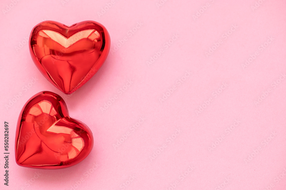 Fototapeta premium Two red hearts on a pink background
