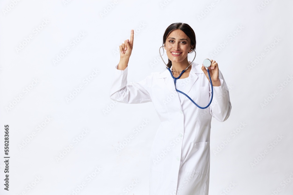 Woman doctor with stethoscope in hand in medical gown on white nurse background, consequences of covid-19, noise in lungs, concept of health and science Woman doctor with stethoscope in hand in medical gown on white nurse background, consequences of covid-19, noise in lungs, concept of health and science
