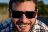 Retrato de hombre apuesto con gafas de sol mirando de cerca a cámara