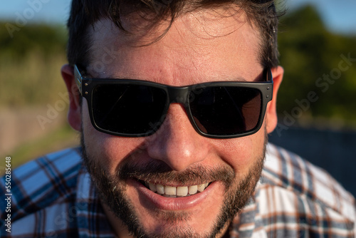 Retrato de hombre apuesto con gafas de sol mirando de cerca a cámara photo