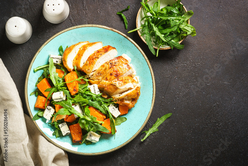 Warm salad with baked chicken breast, pumpkin, blue cheese and arugula. Dash diet, keto diet meal. Top view with copy space.