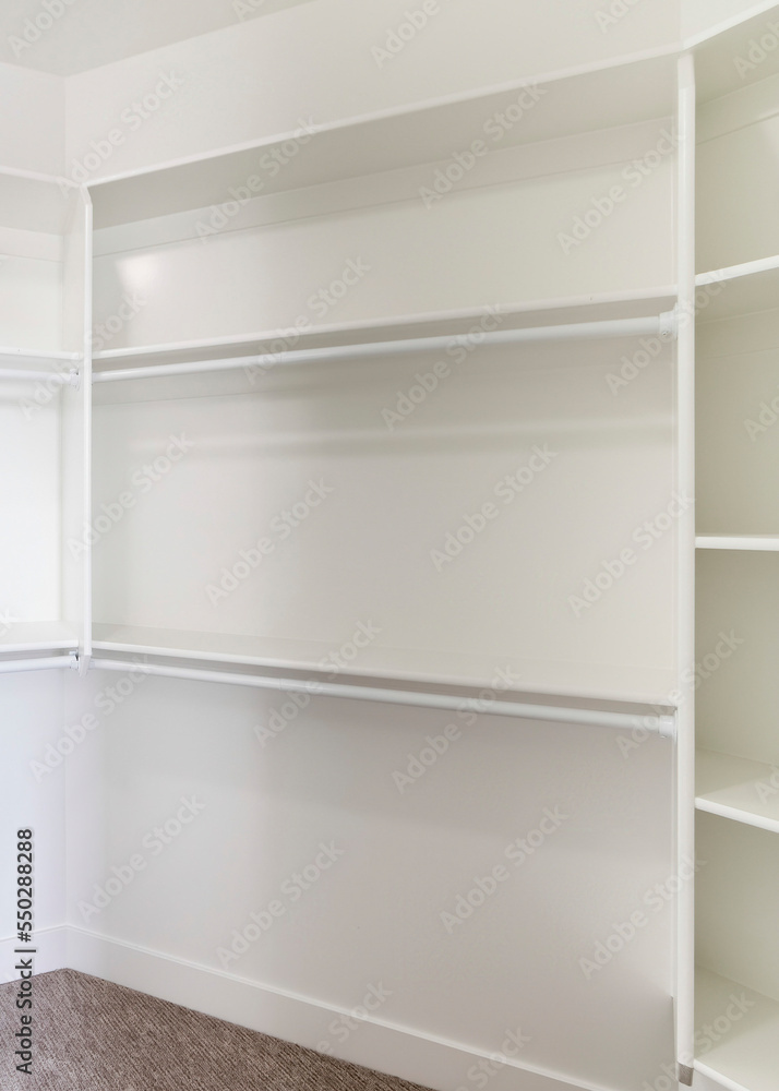 Vertical White built in wall mount shelving unit in a walk in closet Vertical White built in wall mount shelving unit in a walk in closet