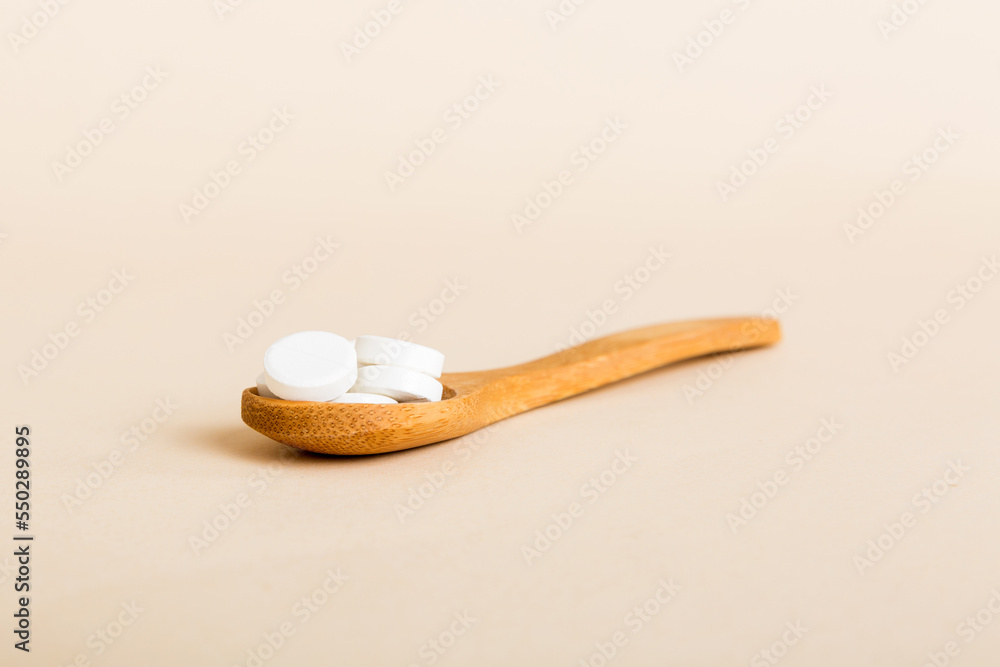 Heap of white pills on colored background. Tablets scattered on a table. Pile of red soft gelatin capsule. Vitamins and dietary supplements concept Heap of white pills on colored background. Tablets scattered on a table. Pile of red soft gelatin capsule. Vitamins and dietary supplements concept