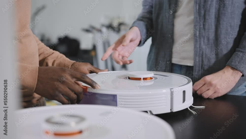 Retail store of consumer electronics. An African chooses a robotic vacuum cleaner. Sales manager, advises the consumer before buying. Modern solutions Retail store of consumer electronics. An African chooses a robotic vacuum cleaner. Sales manager, advises the consumer before buying. Modern solutions