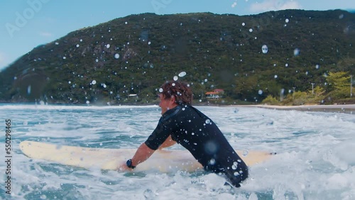 Surfer goes into the ocean through the wave and makes splash