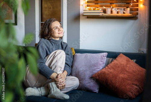 Obraz na płótnie Young adult happy cheerful woman in warm sweater sitting on sofa enjoying resting and relaxing w salonie