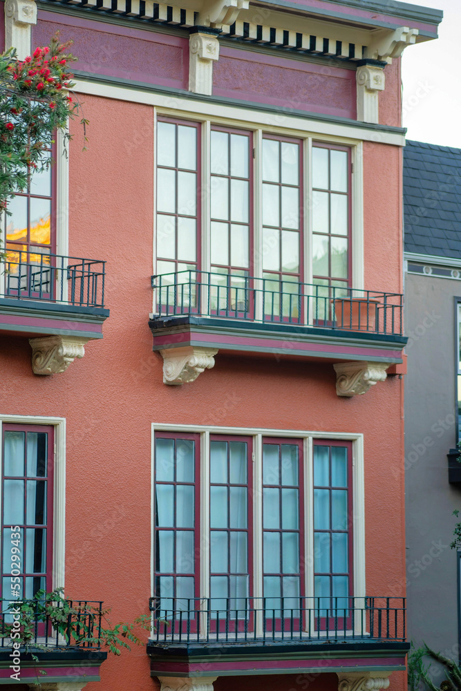 Red or adobe stucco exterior on modern building or home with visible windows and metal grate decorative balconies