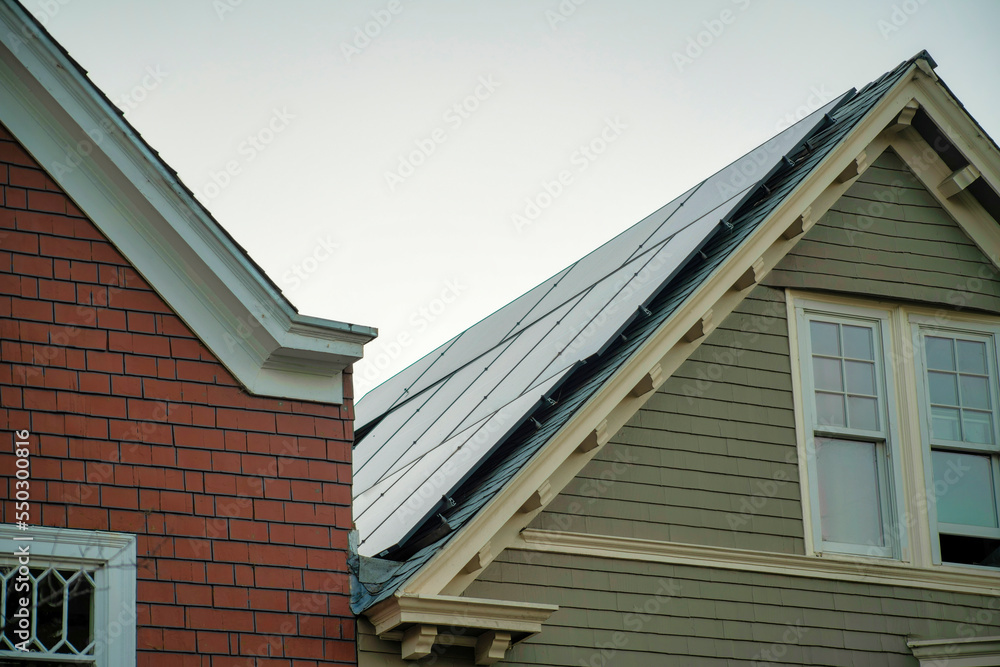 Naklejka premium Modern gable rooftops on homes or houses with wooden slatted exteriors with visible windows and solar pannels in neighborhood