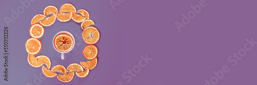 Circle of dried oranges with mug on violet background. Banner.
