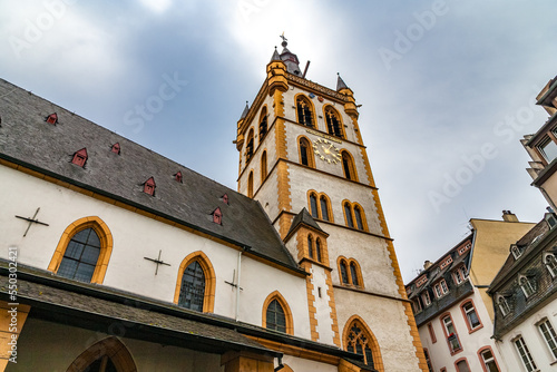 Great view of the church tower of the famous St. Gangolf's Church on a cloudy day in Trier, Germany. In 1507 the two upper floors with the tower gallery and the four small corner towers were added.  photo