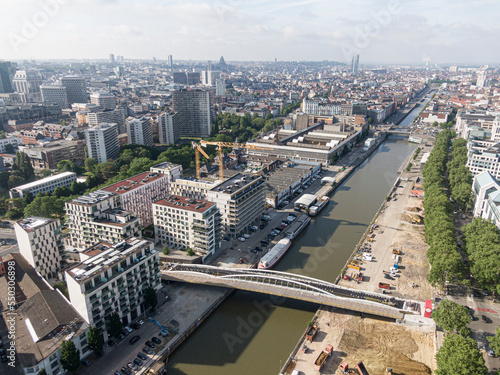 Brussels, Belgium - May 12, 2022: Urban landscape of the city of Brussels. The Senne river canal crossing Brussels and a bridge for cyclists and pedestrians under construction. In the background the o