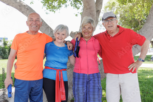 gruppo di anziani felici vestiti con abiti sportivi  si abbraccia in un contesto naturalistico photo