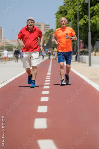 Coppia di anziani in abiti sportivi fa attività fisica in una pista rossa