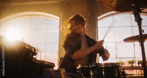 Portrait of a Young Female Playing Drums During a Band Rehearsal in a Loft Studio with Warm Sunlight at Daytime. Drummer Girl Practising Before a Live Concert on Stage in Local Venue.