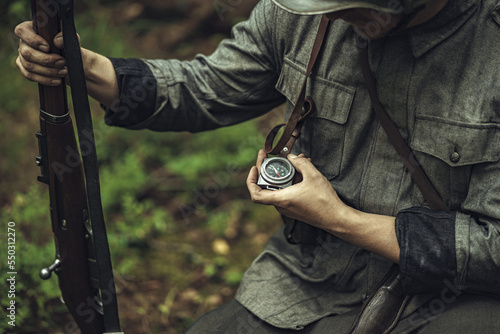 A Finnish army soldier in World War II uniform looks at a compass in the forest.  Military historical reconstruction. Orientation on the terrain by a soldier of the Finnish army.