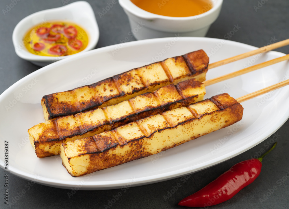 Grilled Rennet or Coalho cheese on a plate with sugar syrup and pepper Grilled Rennet or Coalho cheese on a plate with sugar syrup and pepper