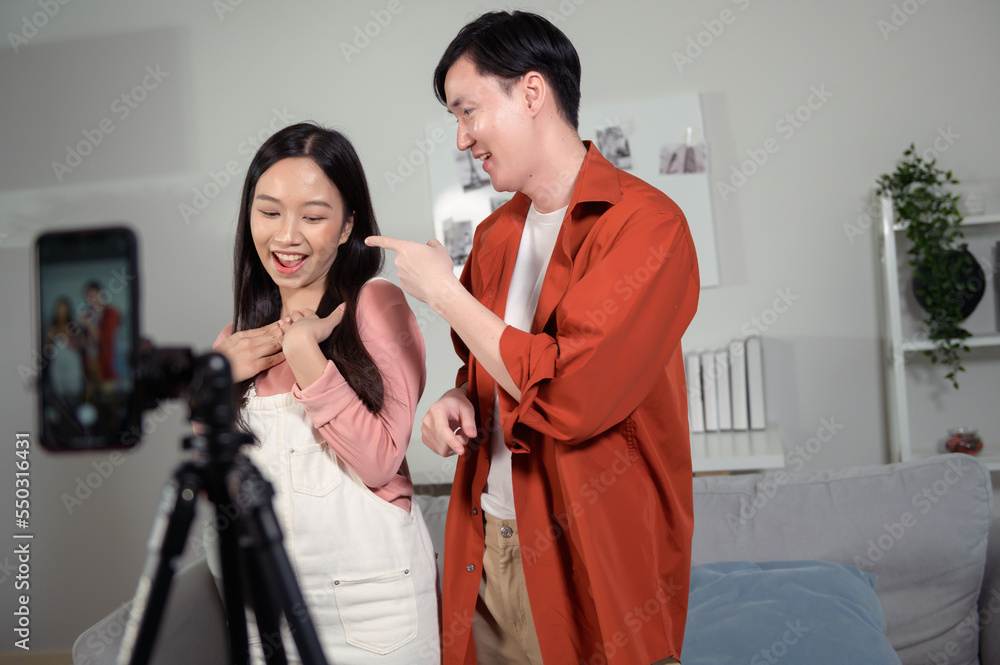 Asian young couple tiktokers are making video dancing via smartphone together, share video content on social media. Asian young couple tiktokers are making video dancing via smartphone together, share video content on social media.