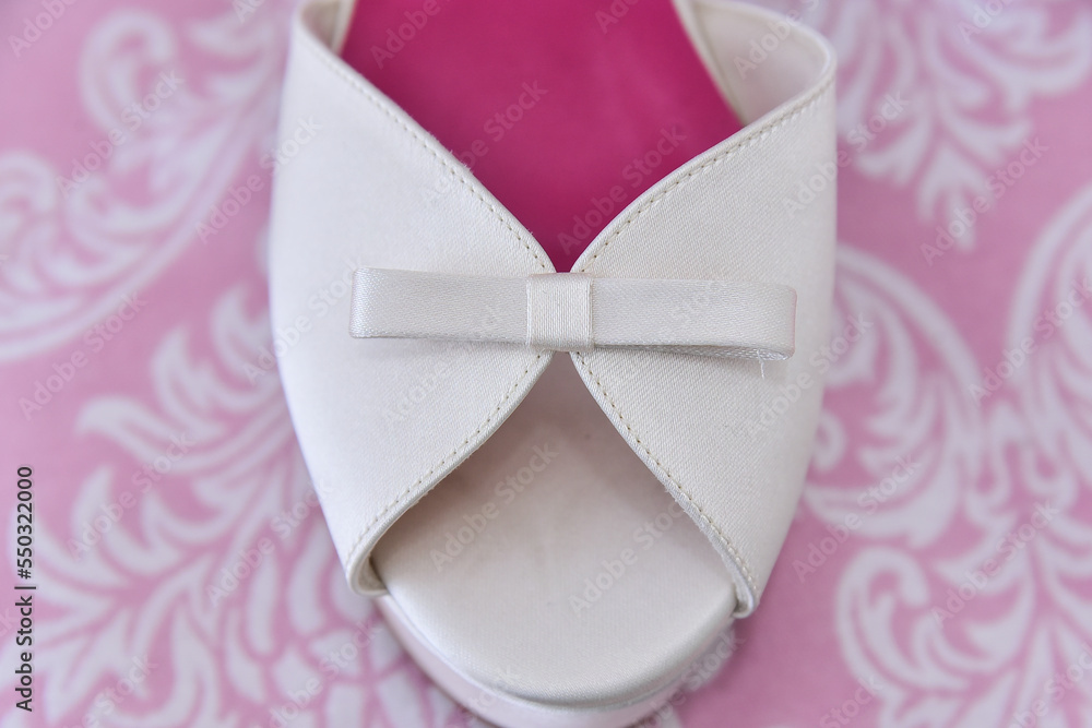 white sandal with bow on pink background

