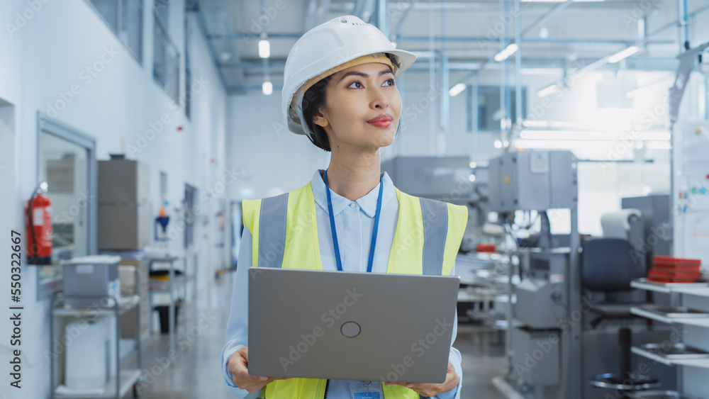 A Happy and Smiling Asian Female Engineer in White Hard Hat Standing with Laptop Computer at Electronic Manufacturing Factory. Successful Employee Watching the Work Flow A Happy and Smiling Asian Female Engineer in White Hard Hat Standing with Laptop Computer at Electronic Manufacturing Factory. Successful Employee Watching the Work Flow