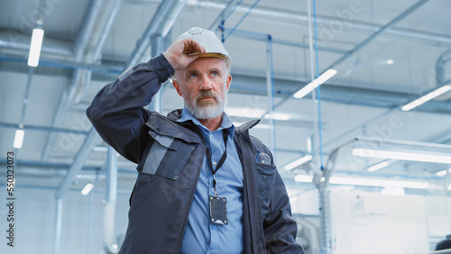 Φωτογραφία Portrait of a Middle Aged, Successful Male Engineer Putting On a White Hard Hat and Safety Glasses, While Walking at Electronics Manufacturing Factory