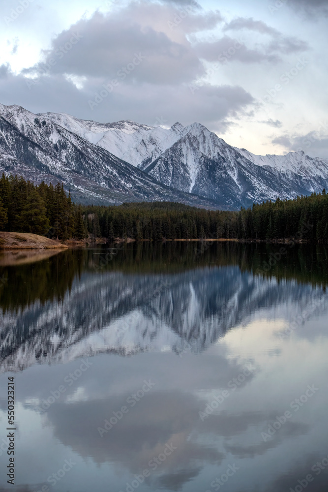 Snow covered Rocky Mountains in Banff National Park in Canada, reflect on the calm lake water.