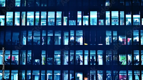 Pattern of office buildings windows illuminated at night. Glass architecture ,corporate building at night - business concept. Blue graphic filter. © Grand Warszawski