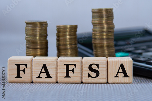 FAFSA - acronym on wooden cubes on the background of coins and calculator photo