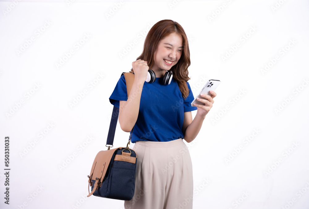 Cute smiling asian girl in blue t-shirt and wireless earphones using her smartphone isolated on white background. Cute smiling asian girl in blue t-shirt and wireless earphones using her smartphone isolated on white background.