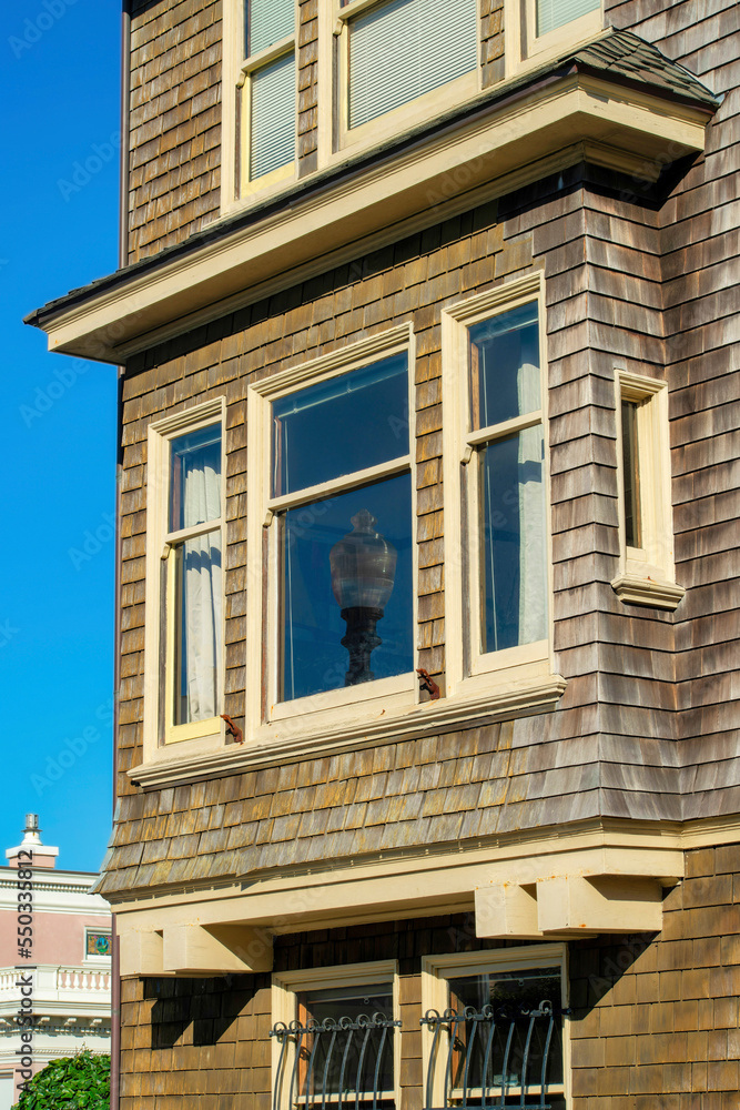 Street lamp visible in window reflection on brown wooden house with slatted wooden pannels in the downtown urban neighborhood Street lamp visible in window reflection on brown wooden house with slatted wooden pannels in the downtown urban neighborhood