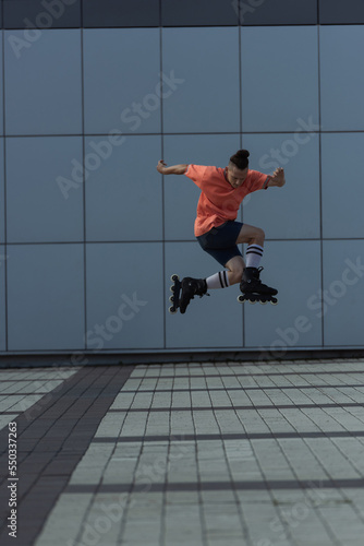 Man in rollers training while jumping on urban street at daytime.