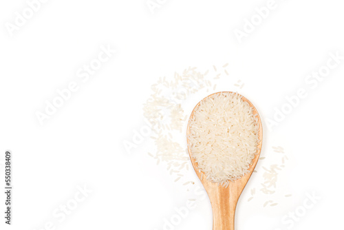 Granos de arroz en una cuchara de madera sobre un fondo de blnaco liso y aislado. Vista superior y de cerca. Copy space.