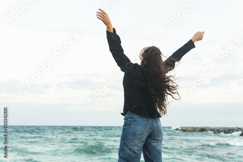 Anonymous content woman with arms stretched on sandy seashore photo