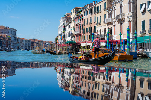 Gondolas on the Grand Canal of Venice on a summer day, reflections of vintage Venetian houses while traveling through the canals of Venice in Italy in summer. Italian architecture and landmarks