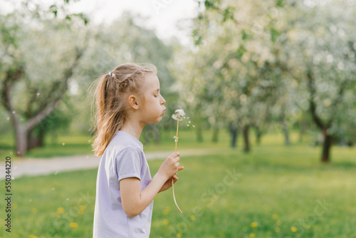 Beautiful child with dandelion flower. Happy kid having fun outdoors in spring park