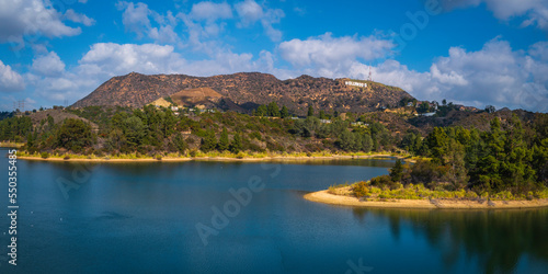 Hollywood Reservoir, Hollywood sign in the background, a tranquil natural park landscape with seagulls in the water and dramatic clouds in the blue sky, in Los Angeles, California  