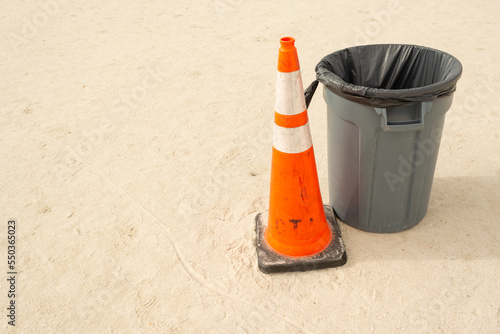 trash can on the beach with a traffic cone