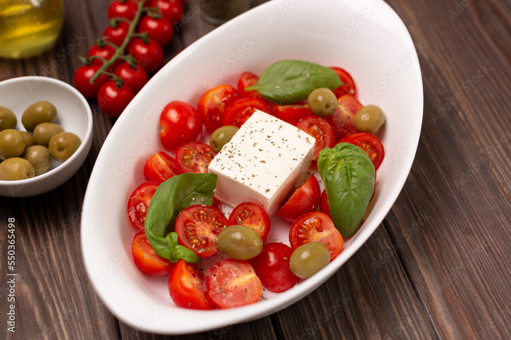 Cherry tomatoes with salted cheese, basil and olives in a deep dish prepared for baking Cherry tomatoes with salted cheese, basil and olives in a deep dish prepared for baking