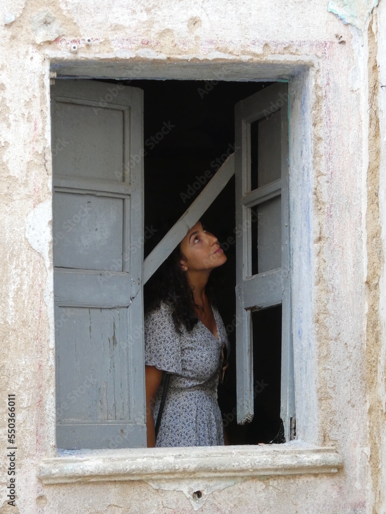 curious woman through antique blue window