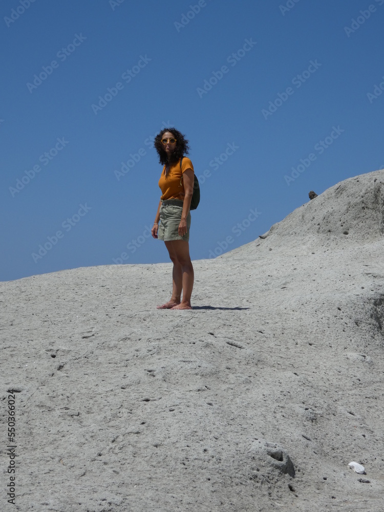 Woman with curly hair whipped by the air in arid landscape.
