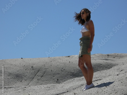 young curly-haired girl posing in a surreal vulcanic moon landscape, Cane Malu at Bosa in Sardinia 