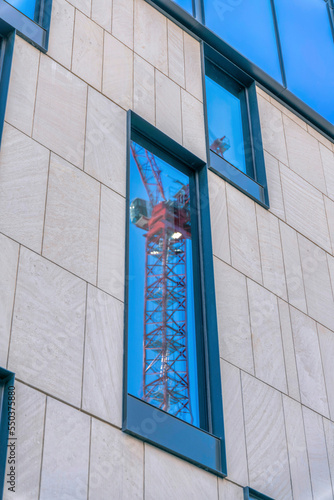 Exterior view of a building with construction crane reflected on the windows © Jason