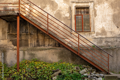 Part of the decoration of the facade of the building and the material from which it is built;  
iron stairs near an old wall with a window