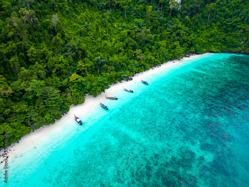 Aerial drone view of famous Monkey Beach at Ko Phi Phi island  Thailand. Tropical beach with white sand  turquoise water and green forest. Long tailed boats are waiting on beach. 