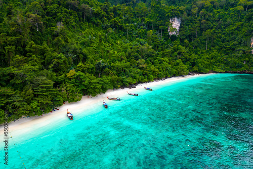 Fototapeta Naklejka Na Ścianę i Meble -  Aerial drone view of famous Monkey Beach at Ko Phi Phi island, Thailand. Tropical beach with white sand, turquoise water and green forest. Long tailed boats are waiting on beach. 