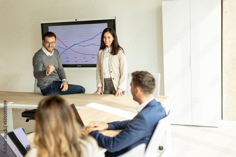 Fototapeta premium Young businesspeople presenting project strategy showing ideas on interactive whiteboard in office