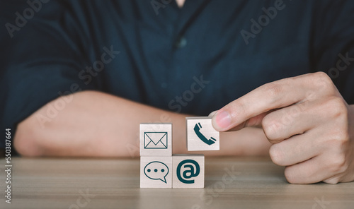 Hand putting wooden cube symbol telephone, email, address. Website page contact us or e-mail marketing concept,work from home and social distance