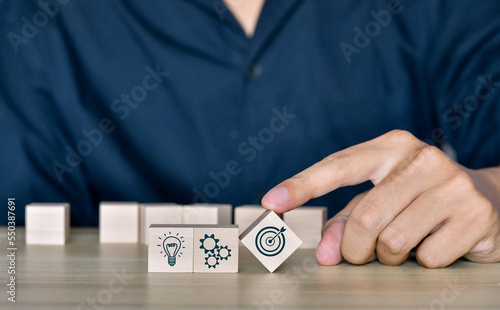 Hand putting virtual target goal and symbol which print screen on wooden cube. Business achievement goal and objective target concept.business strategy, Action plan, Goal and targe