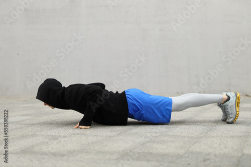 Fitness middle aged man in black hoodie and grey leggings doing push-ups. Copy space. Lifestyle and sports. Side view.
