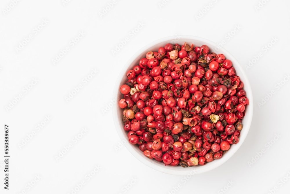 Fragrant spice pink pepper seeds in a small white ceramic bowl with copy space. Pink peppercorn isolated top view with copy space Fragrant spice pink pepper seeds in a small white ceramic bowl with copy space. Pink peppercorn isolated top view with copy space